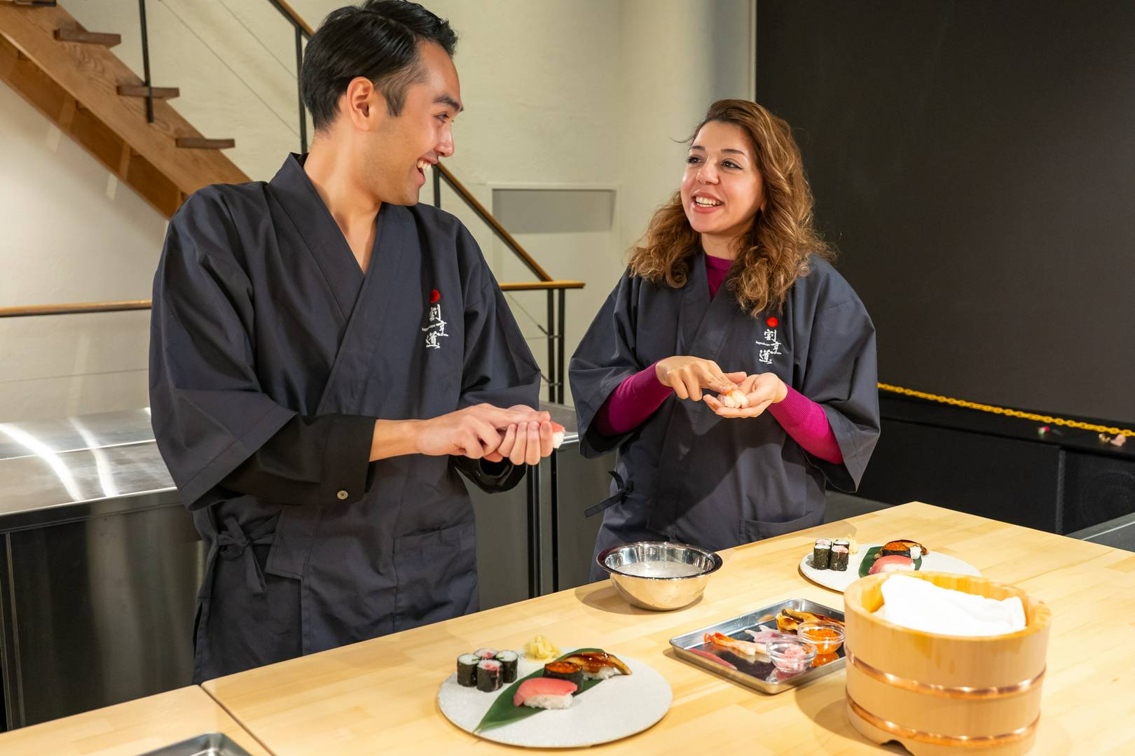 Couple enjoying sushi making class with rolls on wooden table