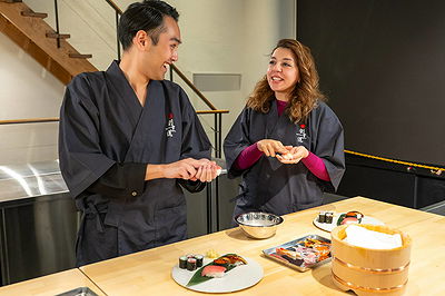 Couple enjoying sushi making class with rolls on wooden table