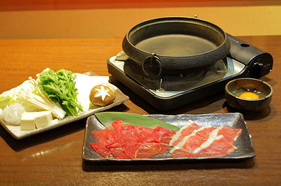 Japanese hot pot setup with fresh meat and vegetables