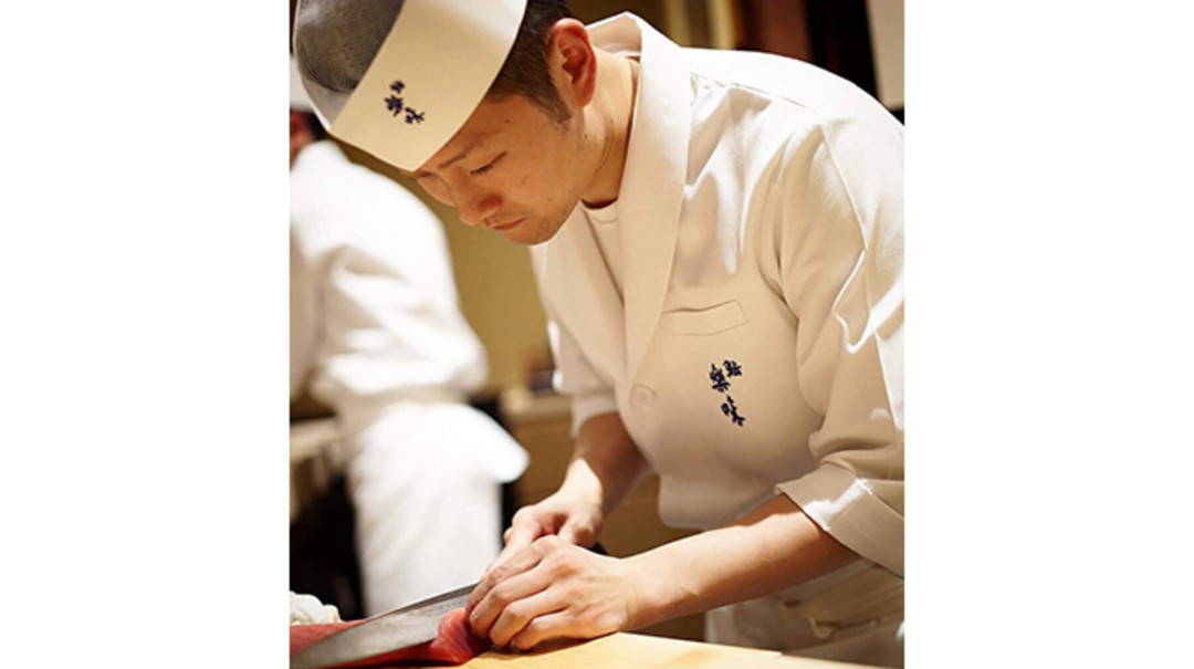 Chef expertly preparing sushi in a traditional restaurant setting.