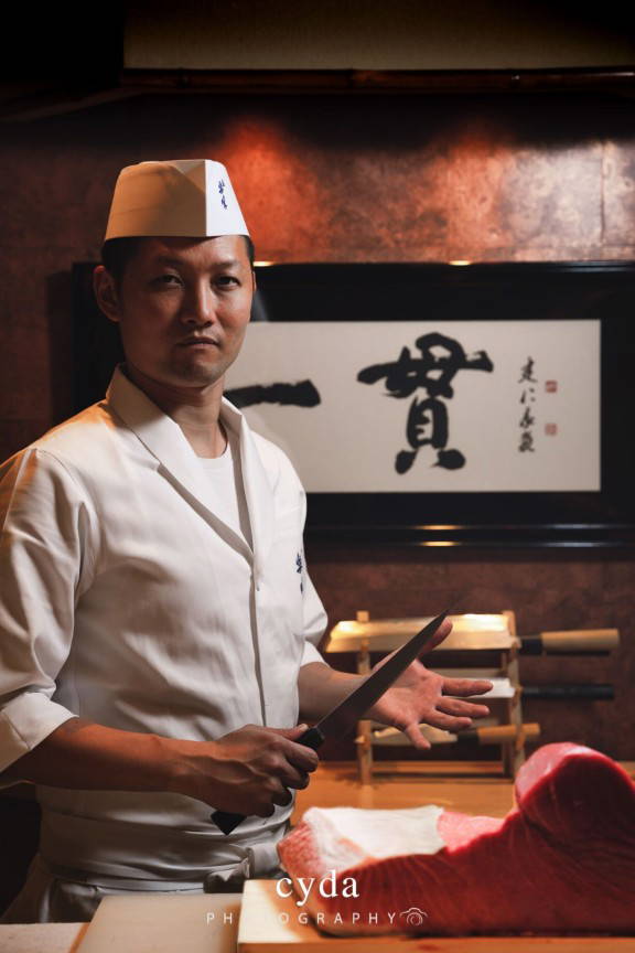 Chef in traditional attire with a knife in a Japanese restaurant