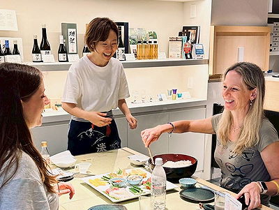 Women enjoy sushi dining experience with smiling chef