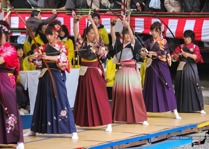 20-year old women in colorful kimonos presenting their splendid archery skills on stage