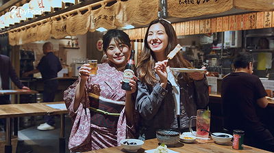 Two women enjoying drinks in a Japanese izakaya