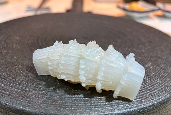 Delicate sushi garnished with salt on a dark textured plate