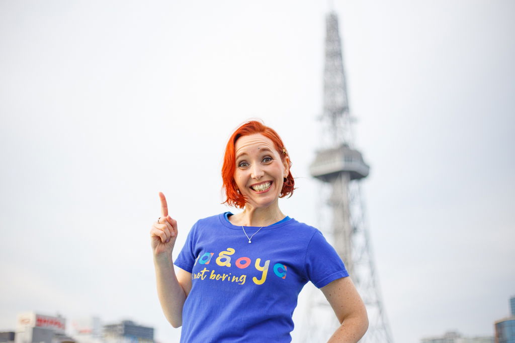 Smiling woman with red hair pointing up, Eiffel Tower backdrop