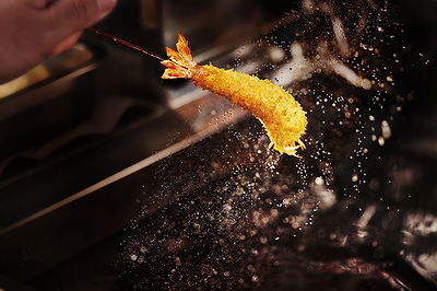 Crispy shrimp tempura being skillfully fried