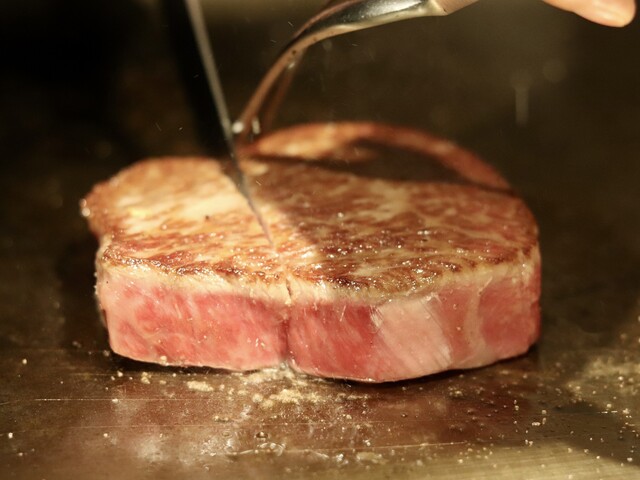 Succulent steak being expertly sliced on a grill