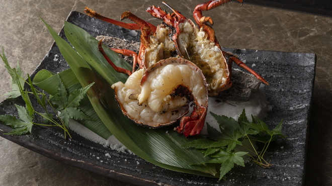 Gourmet lobster dish with herbs and decorative leaf on slate plate