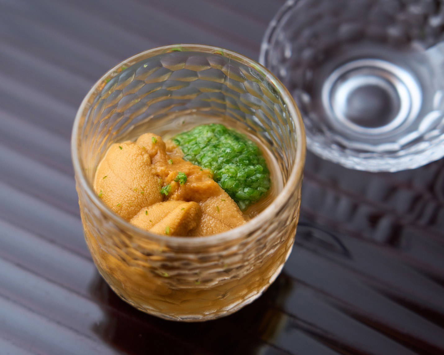 Gourmet sea urchin appetizer in a crystal glass with green garnish
