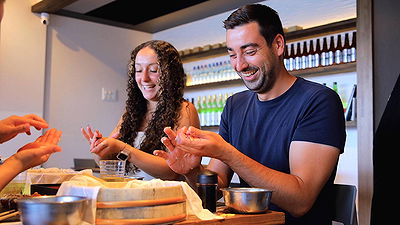 Couple joyfully making sushi rolls in a workshop