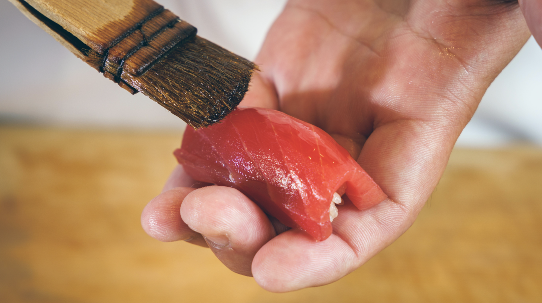Chef glazing tuna sashimi with soy sauce