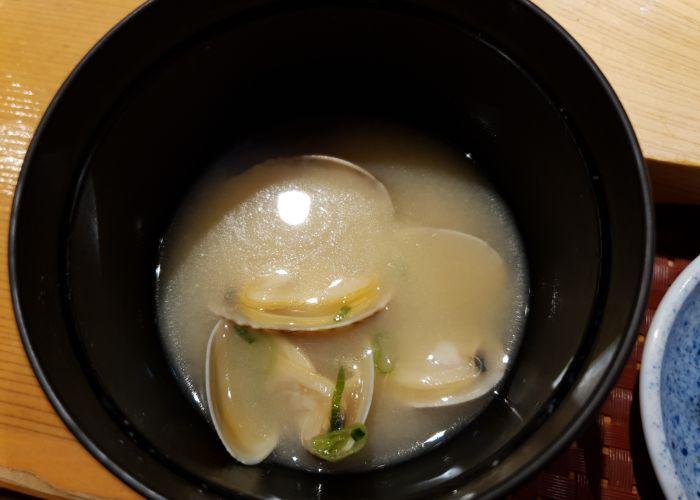 A bowl of miso soup showing three clam shells