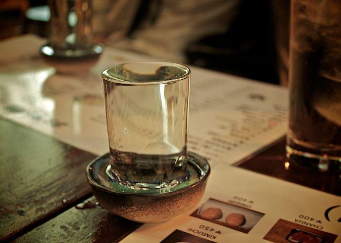 A close up shot of a small glass of sake on a table