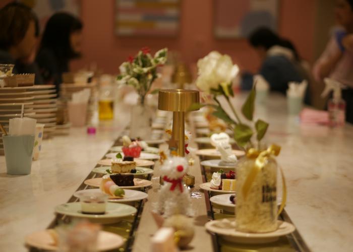 Plates of miniature desserts on the conveyor belt.