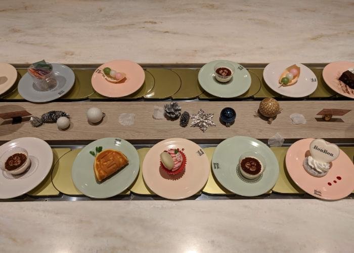 Plates of miniature desserts running on the conveyor belt.