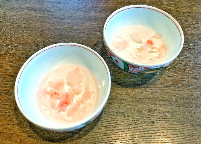 Two blue teacups with cherry blossom petals floating in them