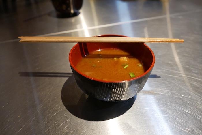Bowl of Nagoya-style red miso soup resting on an aluminum counter