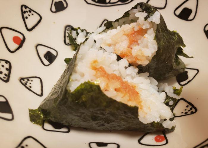 Mentaiko seasoned cod roe onigiri on a backdrop of a plate with onigiri illustrations