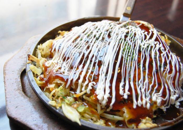 Okonomiyaki, a savory Japanese pancake slathered in sauce and Japanese mayo