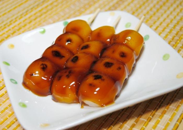 Skewers of mitarashi dango, glazed with a sweet sauce, on a plate