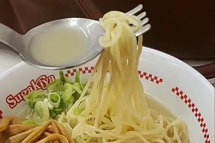 Ramen noodles twirled on spork with broth