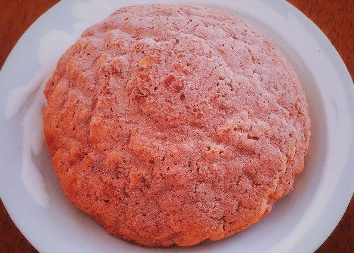 A freshly baked strawberry melon pan is displayed on a plate.