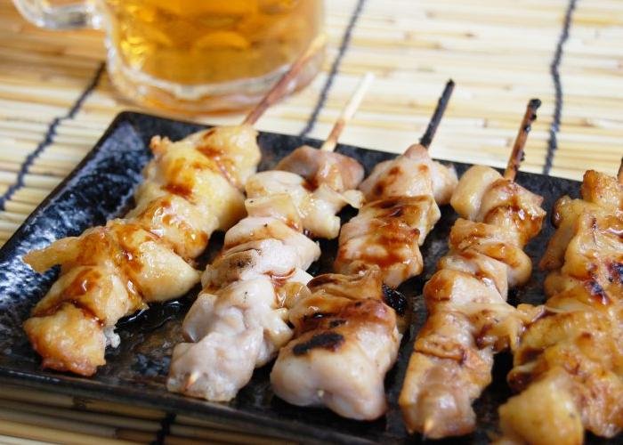 A plate of five yakitori grilled chicken skewers.