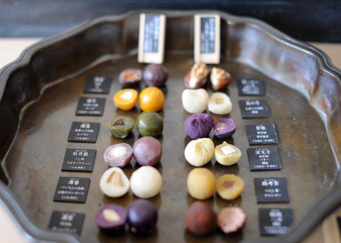 A platter with twelve varieties of colorful mochi sweets, with nuts and other fillings.