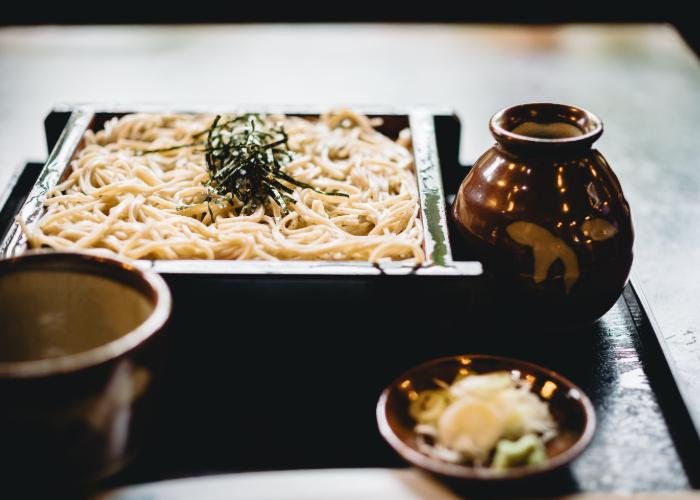 A rectangular tray of soba noodles with thin strips of seaweed.