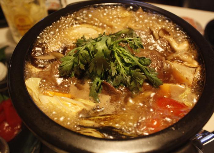 A simmering iron pot of vegetables and meat.