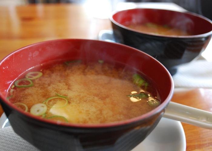 A bowl of miso soup with chopped spring onions.