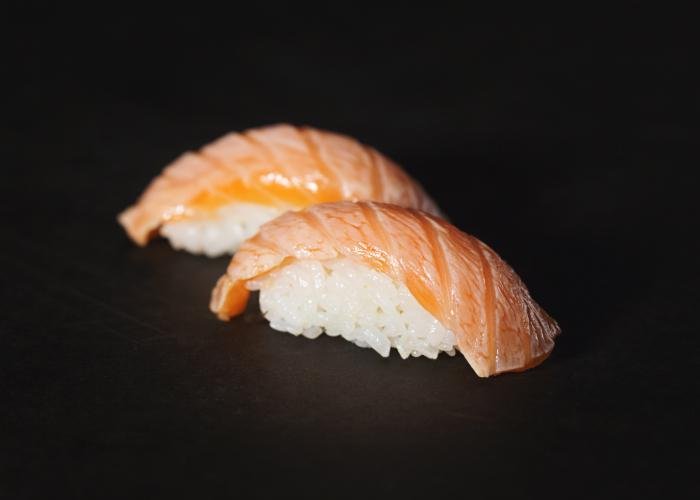 Salmon nigiri sushi against a black background