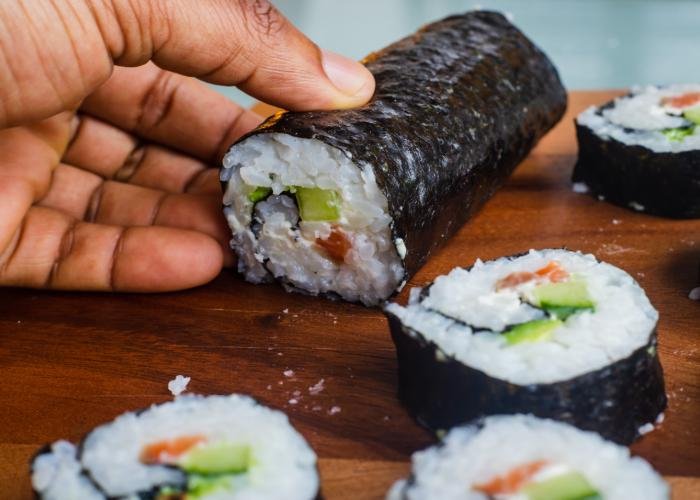 Futomaki roll being cut revealing a colorful interior
