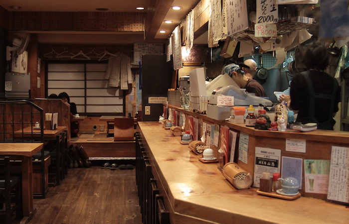 Akaoni 39 Sake Bar in Tokyo with wooden counter, tables, and seated customers