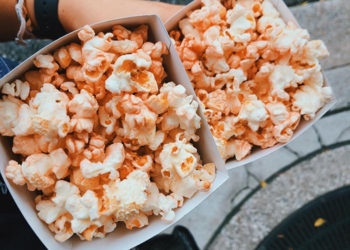 Two filled buckets of garlic shrimp popcorn are held side by side. 