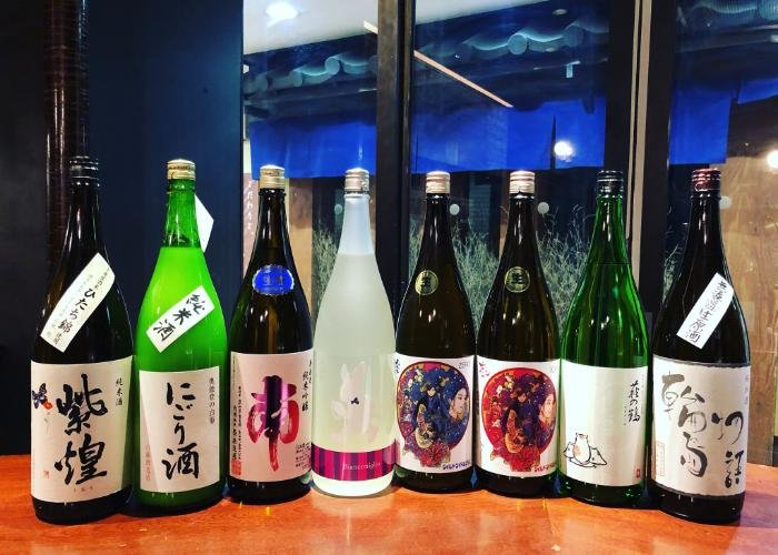 Sake bottles lined up at Nihonshu Stand Moto
