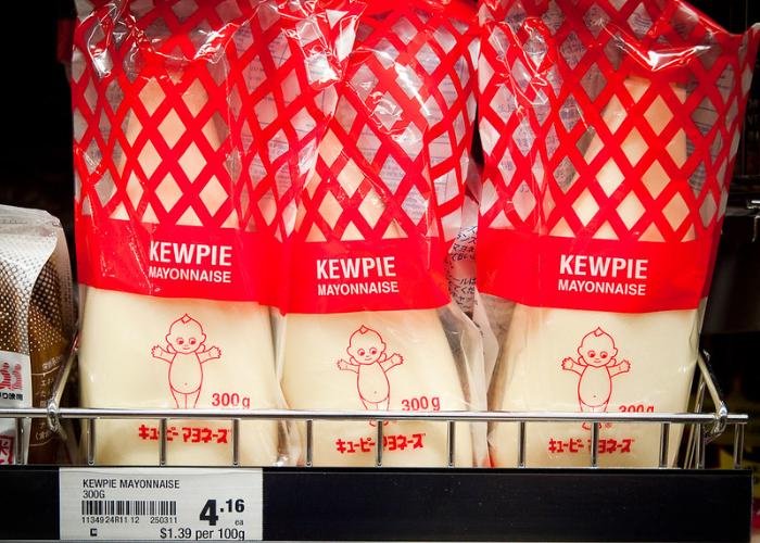 Three bottles of Japanese Kewpie mayonnaise in clear red packaging on store shelf