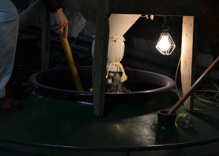 Rice and koji being mixed in a large vat at at a sake brewery