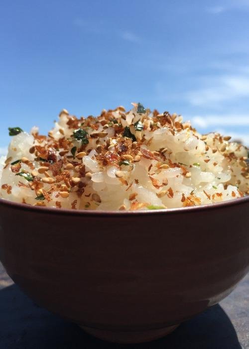 Bowl of rice topped with Furikake against a blue sky