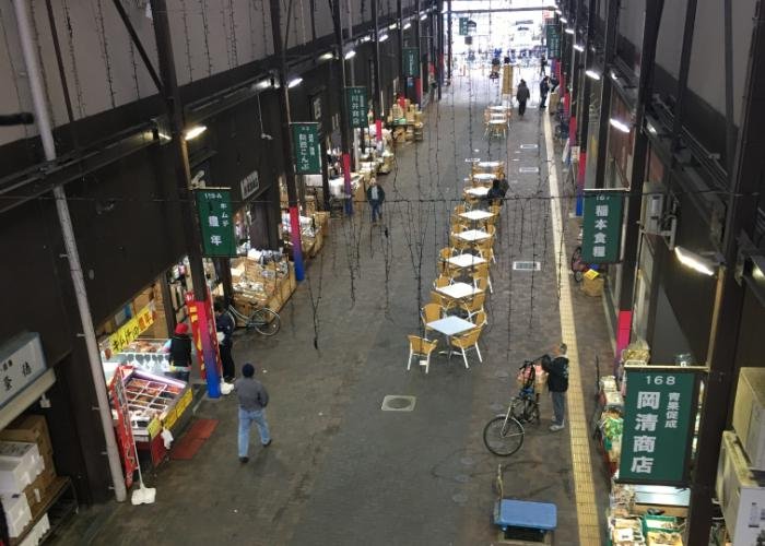 Yellow tables and chairs under cover of the Osaka Kizu Wholesale Market arcade