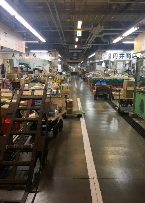 Interior of the Osaka Kizu Market with stacks of boxes containing vegetables and fish 