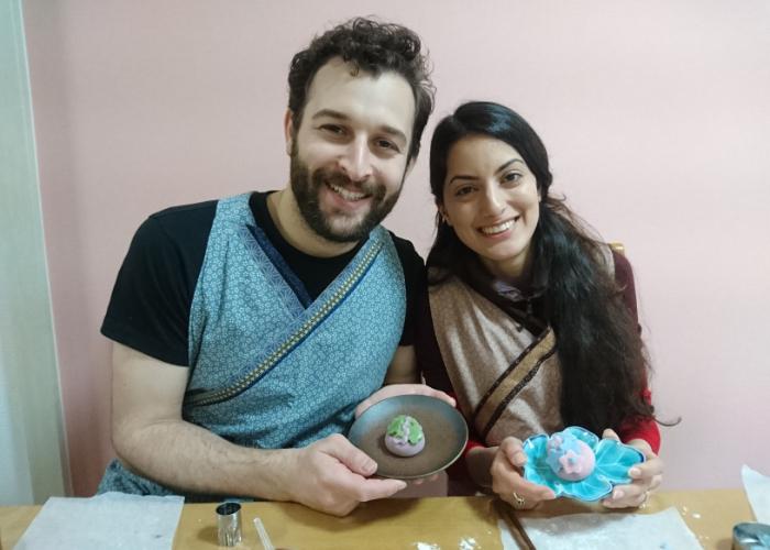 A man and a woman hold up their finished wagashi, Japanese sweets, during a wagashi making class in Osaka