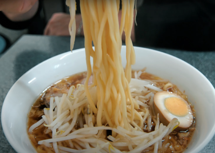 Ramen noodle pull out of a bowl of intense and flavorful shoyu ramen