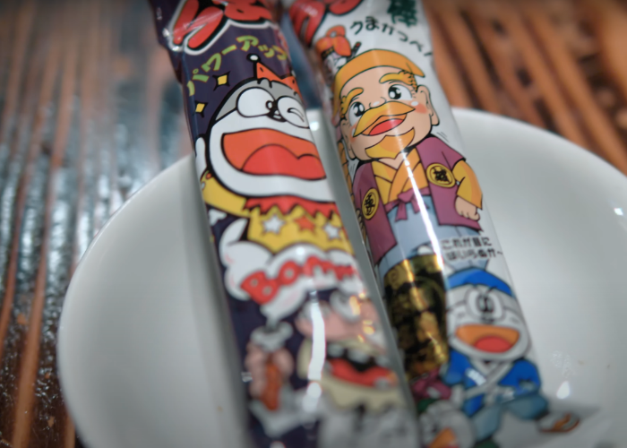 Two sticks of Umaibo snacks on a white plate at a Japanese dagashi bar in Shibuya