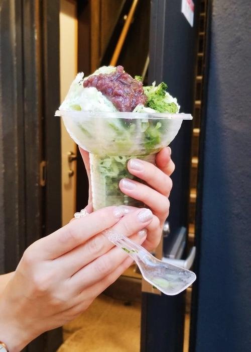 Japanese Kakigori at Ameyoko Market in Ueno, a heaped pile of shaved ice topped with matcha syrup and red bean