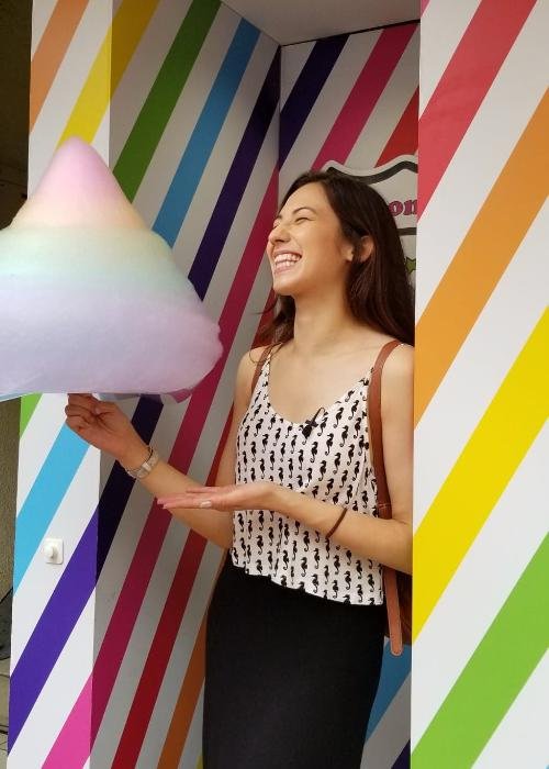 Shizuka Anderson holding a cotton candy rainbow in Harajuku against a striped rainbow background