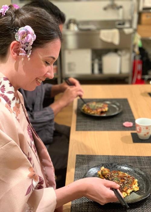 Woman wearing a kimono eats okonomiyaki during the Kyoto Okonomiyaki Cooking Class