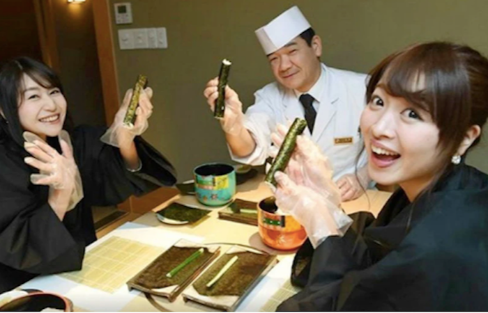 Two girls smiling and holding up sushi during Tokyo Sushi Making Class with a Professional Chef 