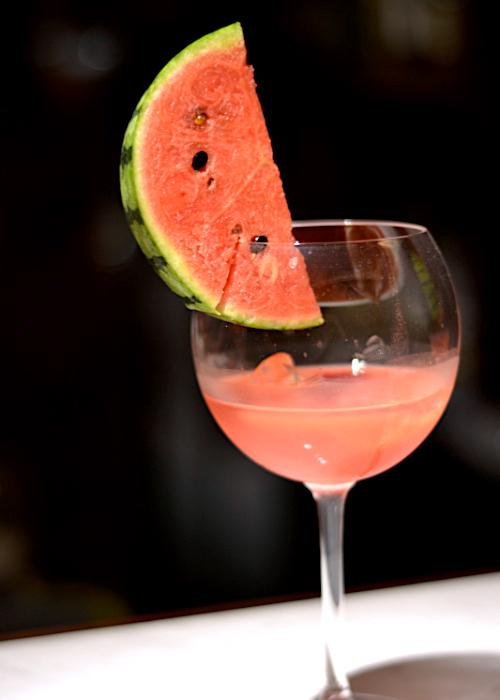 Watermelon shochu cocktail in a long-stemmed glass with a slice of watermelon rimming the glass